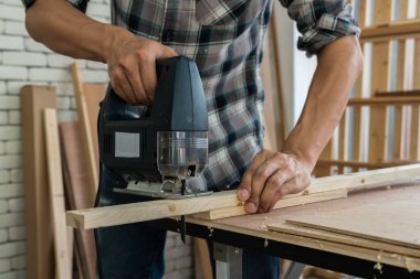 Marangoz atölyede ahşap işçiliği yapıyor. İnşaat malzemesi ya da ahşap mobilya üretiyor. Genç Asyalı marangoz zanaat için profesyonel araçlar kullanır. DIY üreticisi ve marangozluk konsepti.