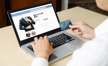 Genç adam, laptop bilgisayar başvurusu ya da web sitesinde online alışveriş yapmak için kredi kartı kullanıyor. E-ticaret ve online alışveriş kavramı.