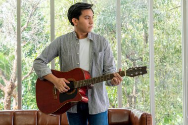 Genç gitarist gitarını evde tutuyor. Müzik ve şarkı konsepti.