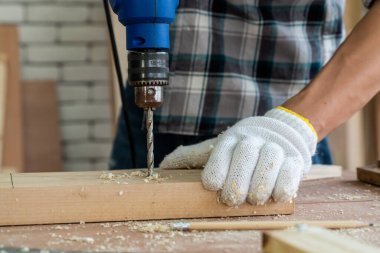 Marangoz atölyede ahşap işçiliği yapıyor. İnşaat malzemesi ya da ahşap mobilya üretiyor. Genç Asyalı marangoz zanaat için profesyonel araçlar kullanır. DIY üreticisi ve marangozluk konsepti.