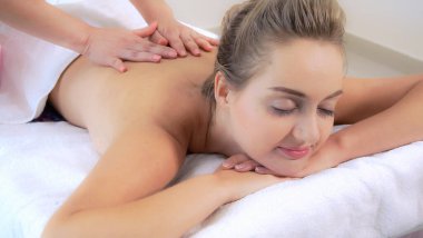 Rahat bir kadın profesyonel masaj terapistiyle lüks kaplıcalarda masaj yaptırıyor. Sağlık, şifa ve rahatlama konsepti.