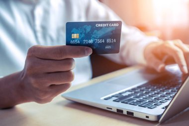 Genç adam, laptop bilgisayar başvurusu ya da web sitesinde online alışveriş yapmak için kredi kartı kullanıyor. E-ticaret ve online alışveriş kavramı.