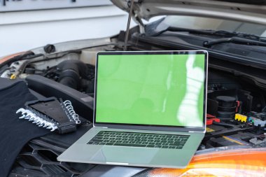 Motor kontrolü için arabanın kaputunda dizüstü bilgisayar var. Garaj tamiri konsepti.