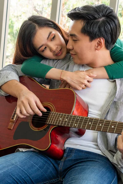 若いアジアのカップルは 一緒に自宅のリビングルームでギターと歌を再生します 音楽とライフスタイルのコンセプト — ストック写真
