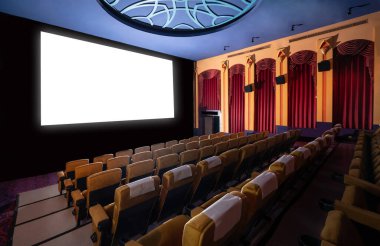 Sinematograftan yansıtılan beyaz ekranı gösteren sinema salonundaki koltukların önündeki sinema ekranı. Sinema klasik stil ile dekore edilmiştir. Lüks sinema izleme duygusu için..
