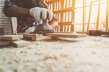 Marangoz atölyede ahşap işçiliği yapıyor. İnşaat malzemesi ya da ahşap mobilya üretiyor. Genç Asyalı marangoz zanaat için profesyonel araçlar kullanır. DIY üreticisi ve marangozluk konsepti.