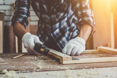 Marangoz atölyede ahşap işçiliği yapıyor. İnşaat malzemesi ya da ahşap mobilya üretiyor. Genç Asyalı marangoz zanaat için profesyonel araçlar kullanır. DIY üreticisi ve marangozluk konsepti.