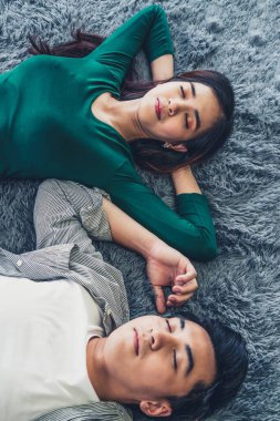 Mutlu Asyalı çift oturma odasının zemininde birlikte yatıyorlar. Aşk ilişkisi ve yaşam tarzı kavramı.