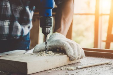 Marangoz atölyede ahşap işçiliği yapıyor. İnşaat malzemesi ya da ahşap mobilya üretiyor. Genç Asyalı marangoz zanaat için profesyonel araçlar kullanır. DIY üreticisi ve marangozluk konsepti.