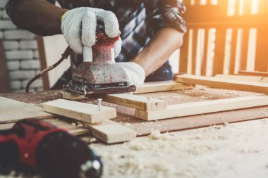 Marangoz atölyede ahşap işçiliği yapıyor. İnşaat malzemesi ya da ahşap mobilya üretiyor. Genç Asyalı marangoz zanaat için profesyonel araçlar kullanır. DIY üreticisi ve marangozluk konsepti.