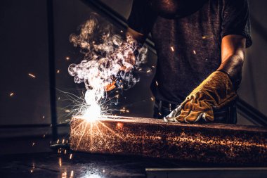 Fabrikada çelik kaynak makinesiyle çalışan metal kaynakçı güvenlik ekipmanı takıyor. El becerisi iş gücü kavramına göre metal imalatı ve inşaat bakım hizmeti.