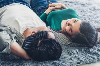 Mutlu Asyalı çift oturma odasının zemininde birlikte yatıyorlar. Aşk ilişkisi ve yaşam tarzı kavramı.