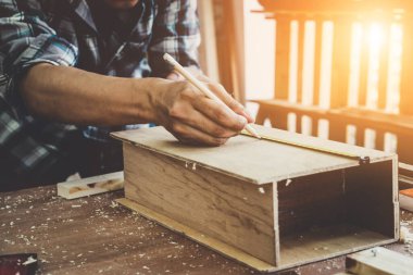 Marangoz atölyede ahşap işçiliği yapıyor. İnşaat malzemesi ya da ahşap mobilya üretiyor. Genç Asyalı marangoz zanaat için profesyonel araçlar kullanır. DIY üreticisi ve marangozluk konsepti.