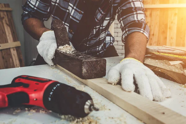 Marangoz atölyede ahşap işçiliği yapıyor. İnşaat malzemesi ya da ahşap mobilya üretiyor. Genç Asyalı marangoz zanaat için profesyonel araçlar kullanır. DIY üreticisi ve marangozluk konsepti.