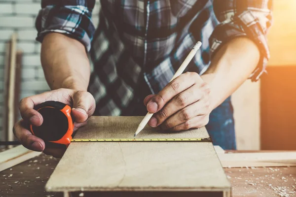 Marangoz atölyede ahşap işçiliği yapıyor. İnşaat malzemesi ya da ahşap mobilya üretiyor. Genç Asyalı marangoz zanaat için profesyonel araçlar kullanır. DIY üreticisi ve marangozluk konsepti.
