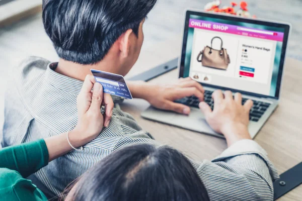 Young couple use credit card for online shopping on internet website at home. Number on the credit card is mock up. No personal information shown on the credit card. Online business shopping concept.