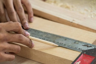Marangoz atölyede ahşap işçiliği yapıyor. İnşaat malzemesi ya da ahşap mobilya üretiyor. Genç Asyalı marangoz zanaat için profesyonel araçlar kullanır. DIY üreticisi ve marangozluk konsepti.