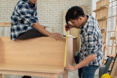Marangoz atölyede ahşap işçiliği yapıyor. İnşaat malzemesi ya da ahşap mobilya üretiyor. Genç Asyalı marangoz zanaat için profesyonel araçlar kullanır. DIY üreticisi ve marangozluk konsepti.