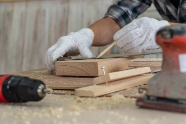 Marangoz atölyede ahşap işçiliği yapıyor. İnşaat malzemesi ya da ahşap mobilya üretiyor. Genç Asyalı marangoz zanaat için profesyonel araçlar kullanır. DIY üreticisi ve marangozluk konsepti.