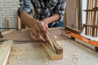 Marangoz atölyede ahşap işçiliği yapıyor. İnşaat malzemesi ya da ahşap mobilya üretiyor. Genç Asyalı marangoz zanaat için profesyonel araçlar kullanır. DIY üreticisi ve marangozluk konsepti.