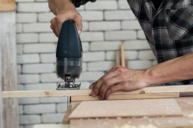 Marangoz atölyede ahşap işçiliği yapıyor. İnşaat malzemesi ya da ahşap mobilya üretiyor. Genç Asyalı marangoz zanaat için profesyonel araçlar kullanır. DIY üreticisi ve marangozluk konsepti.