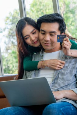 Genç çift evdeki internet sitesinden online alışveriş için kredi kartını kullanıyor. Kredi kartındaki numara sahte. Kredi kartında kişisel bilgi yok. Çevrimiçi iş alışveriş kavramı.