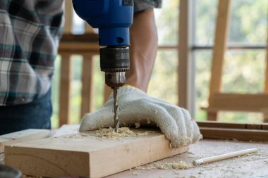 Marangoz atölyede ahşap işçiliği yapıyor. İnşaat malzemesi ya da ahşap mobilya üretiyor. Genç Asyalı marangoz zanaat için profesyonel araçlar kullanır. DIY üreticisi ve marangozluk konsepti.