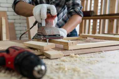 Marangoz atölyede ahşap işçiliği yapıyor. İnşaat malzemesi ya da ahşap mobilya üretiyor. Genç Asyalı marangoz zanaat için profesyonel araçlar kullanır. DIY üreticisi ve marangozluk konsepti.