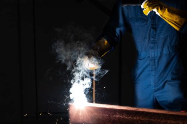 Fabrikada çelik kaynak makinesiyle çalışan metal kaynakçı güvenlik ekipmanı takıyor. El becerisi iş gücü kavramına göre metal imalatı ve inşaat bakım hizmeti.