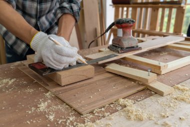 Marangoz atölyede ahşap işçiliği yapıyor. İnşaat malzemesi ya da ahşap mobilya üretiyor. Genç Asyalı marangoz zanaat için profesyonel araçlar kullanır. DIY üreticisi ve marangozluk konsepti.