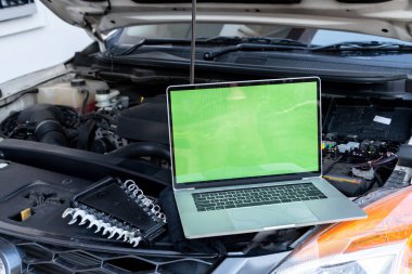 Motor kontrolü için arabanın kaputunda dizüstü bilgisayar var. Garaj tamiri konsepti.