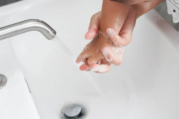 Mother wash baby hand for prevention of novel Coronavirus Disease 2019 or COVID-19 . People wash hands at bathroom sink to clean the virus infection.