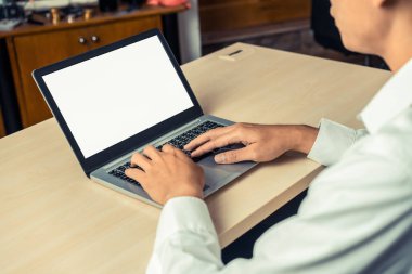 Masada otururken dizüstü bilgisayar kullanan iş adamı ya da ofis çalışanı.