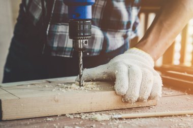 Marangoz atölyede ahşap işçiliği yapıyor. İnşaat malzemesi ya da ahşap mobilya üretiyor. Genç Asyalı marangoz zanaat için profesyonel araçlar kullanır. DIY üreticisi ve marangozluk konsepti.