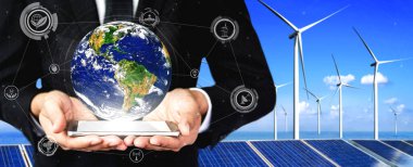 Alternatif enerji ile sürdürülebilirlik gelişimi kavramı. Çevre dostu rüzgar türbini çiftliği ve arka planda yeşil yenilenebilir enerji ile insan eliyle dünya ile ilgilenin..