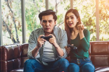 Genç mutlu Asyalı çift oturma odasında video oyunu oynuyor. Neşeli insanlar bilgisayar oyunu konseptiyle eğleniyor..