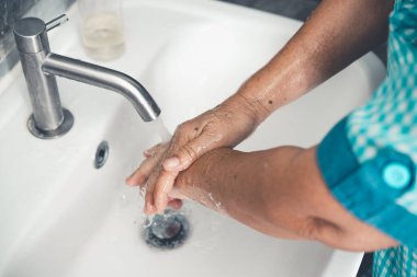 Üst düzey kadın, Coronavirus hastalığı 2019 ya da COVID-19 'u önlemek için elini yıkıyor. İnsanlar virüs enfeksiyonunu temizlemek için lavaboda ellerini yıkıyor..