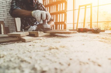 Marangoz atölyede ahşap işçiliği yapıyor. İnşaat malzemesi ya da ahşap mobilya üretiyor. Genç Asyalı marangoz zanaat için profesyonel araçlar kullanır. DIY üreticisi ve marangozluk konsepti.