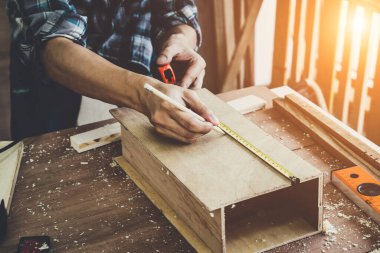 Marangoz atölyede ahşap işçiliği yapıyor. İnşaat malzemesi ya da ahşap mobilya üretiyor. Genç Asyalı marangoz zanaat için profesyonel araçlar kullanır. DIY üreticisi ve marangozluk konsepti.