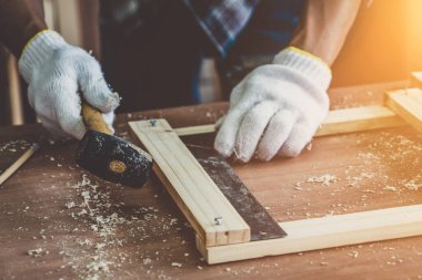 Marangoz atölyede ahşap işçiliği yapıyor. İnşaat malzemesi ya da ahşap mobilya üretiyor. Genç Asyalı marangoz zanaat için profesyonel araçlar kullanır. DIY üreticisi ve marangozluk konsepti.