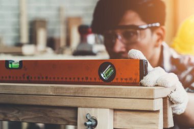 Marangoz atölyede ahşap işçiliği yapıyor. İnşaat malzemesi ya da ahşap mobilya üretiyor. Genç Asyalı marangoz zanaat için profesyonel araçlar kullanır. DIY üreticisi ve marangozluk konsepti.