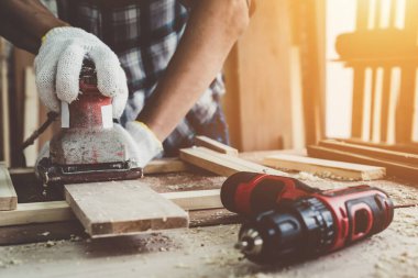 Marangoz atölyede ahşap işçiliği yapıyor. İnşaat malzemesi ya da ahşap mobilya üretiyor. Genç Asyalı marangoz zanaat için profesyonel araçlar kullanır. DIY üreticisi ve marangozluk konsepti.