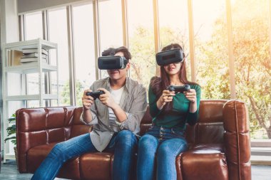 Genç mutlu Asyalı çift oturma odasında video oyunu oynuyor. Neşeli insanlar bilgisayar oyunu konseptiyle eğleniyor..