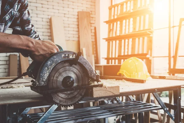 Carpenter working on wood craft at workshop to produce construction material or wooden furniture. The young Asian carpenter use professional tools for crafting. DIY maker and carpentry work concept.