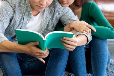 Genç Asyalı çift oturma odasında kitap okuyor. Aşk ilişkisi ve yaşam tarzı kavramı.