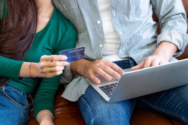 Genç çift evdeki internet sitesinden online alışveriş için kredi kartını kullanıyor. Kredi kartındaki numara sahte. Kredi kartında kişisel bilgi yok. Çevrimiçi iş alışveriş kavramı.