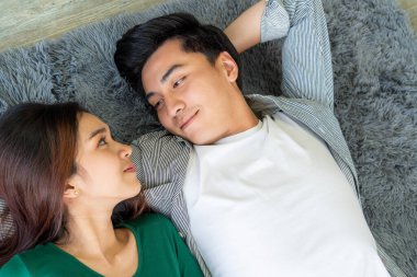 Mutlu Asyalı çift oturma odasının zemininde birlikte yatıyorlar. Aşk ilişkisi ve yaşam tarzı kavramı.