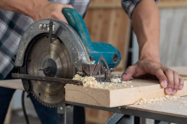 Marangoz atölyede ahşap işçiliği yapıyor. İnşaat malzemesi ya da ahşap mobilya üretiyor. Genç Asyalı marangoz zanaat için profesyonel araçlar kullanır. DIY üreticisi ve marangozluk konsepti.