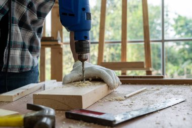 Marangoz atölyede ahşap işçiliği yapıyor. İnşaat malzemesi ya da ahşap mobilya üretiyor. Genç Asyalı marangoz zanaat için profesyonel araçlar kullanır. DIY üreticisi ve marangozluk konsepti.