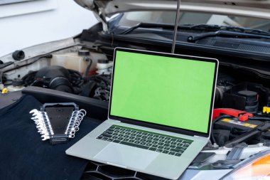 Motor kontrolü için arabanın kaputunda dizüstü bilgisayar var. Garaj tamiri konsepti.